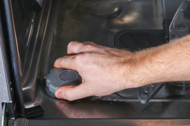 Adam bulaşık makinesindeki tuz için kabı açar ve özel tuzu doldurur..