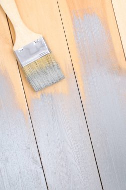 Elinde boya olan fırça. Bir adam tahta tahtaları gri boya fırçasıyla boyuyor..