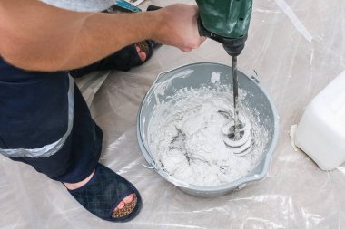 Erkek bir işçi macun karışımını yayar ve duvarı düzleştirir..