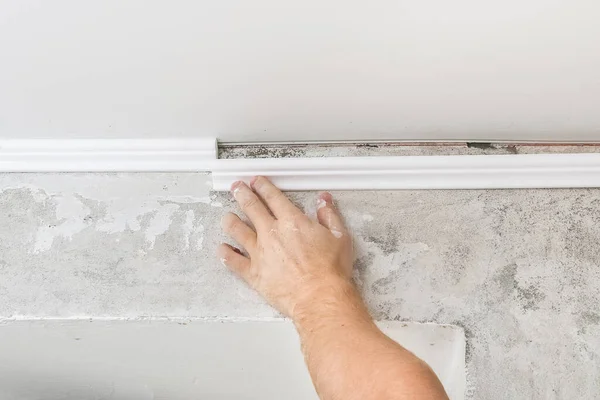 Worker fixes the plastic molding to ceiling. Installation of ceiling cornice. — Stock Photo, Image
