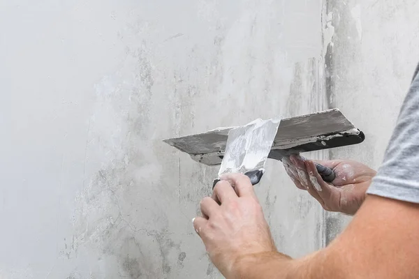 Ein männlicher Arbeiter verteilt die Spachtelmasse und glättet die Wand. — Stockfoto