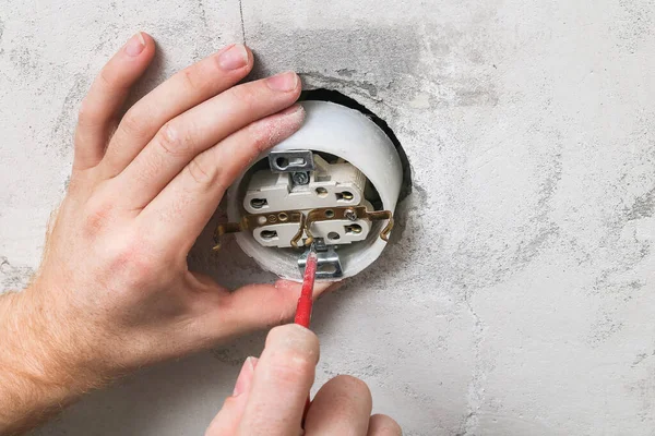 Um homem desmonta e conserta a tomada elétrica para reparos. Tomada de energia. — Fotografia de Stock