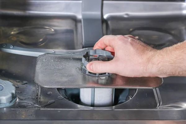 Man unscrews the filter for cleaning in dishwasher. — Stock Photo, Image