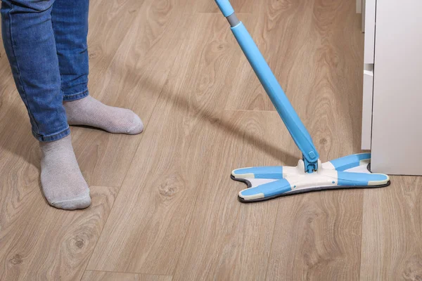 Ein Mann wäscht den Fußboden mit einem Wischmopp im Zimmer. Unter dem Bett. Reinigung. — Stockfoto