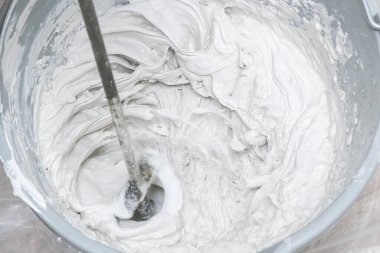 Erkek bir işçi macun karışımını yayar ve duvarı düzleştirir..