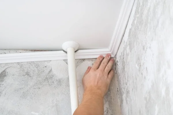 İşçi tavandaki plastik pervazları tamir ediyor. Tavan kipinin kurulumu.