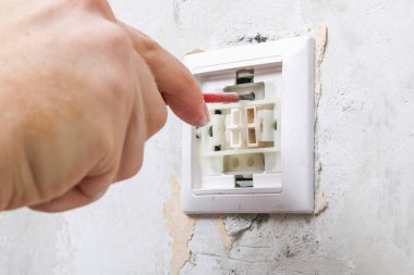 Bir işçi duvar kağıtları için ışık düğmesini kaldırır.