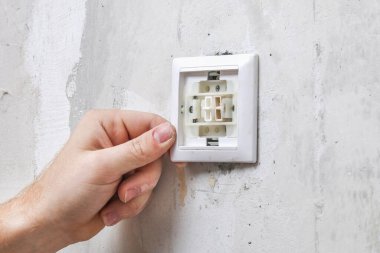 Bir işçi duvar kağıtları için ışık düğmesini kaldırır.