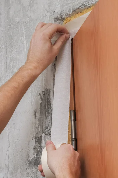 O homem cola uma fita de papel branco. Close-up. Renovação na casa. — Fotografia de Stock