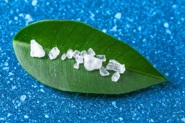 Mavi masadaki kaba tuz kristalleri. Deniz tuzu. Tuzlu reklamlar için arka plan.