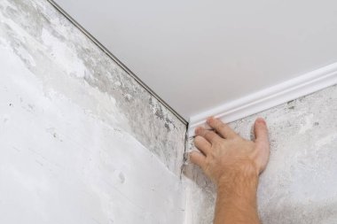 İşçi tavandaki plastik pervazları tamir ediyor. Tavan kipinin kurulumu.