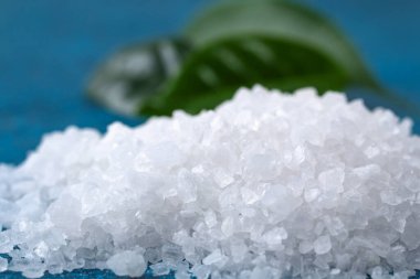 Mavi masadaki kaba tuz kristalleri. Deniz tuzu. Tuzlu reklamlar için arka plan.