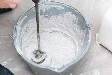 Erkek bir işçi macun karışımını yayar ve duvarı düzleştirir..