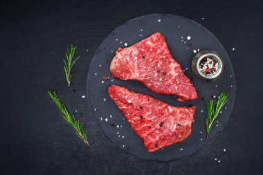 Biberiye ve baharatlı çiğ biftek, koyu siyah arka plan, üst manzara. Taze ızgara.