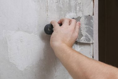 Adam odadaki duvarları alçılıyor. Yakın plan..