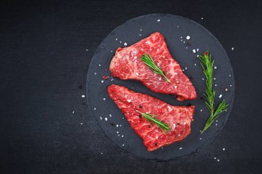 Biberiye ve baharatlı çiğ biftek, koyu siyah arka plan, üst manzara. Taze ızgara.