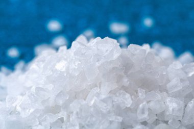 Mavi masadaki kaba tuz kristalleri. Deniz tuzu. Tuzlu reklamlar için arka plan.