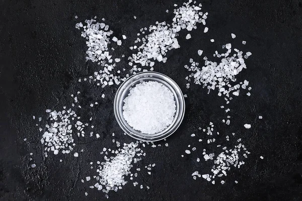 Πυκνοί κρύσταλλοι αλατιού σε μαύρο τραπέζι. Μπολ με θαλασσινό αλάτι. Ιστορικό για διαφήμιση αλμυρή. — Φωτογραφία Αρχείου