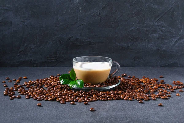 Taza de café en una mesa gris con granos de café y hojas de café. —  Fotos de Stock
