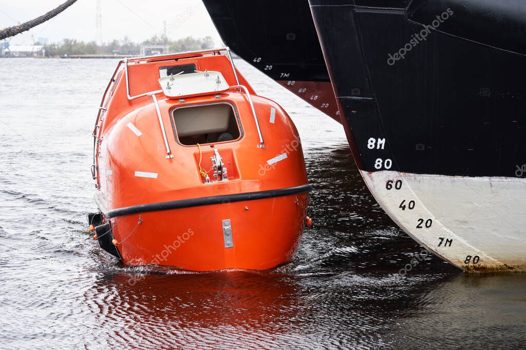 Totally Enclosed Lifeboat floating near big vessel