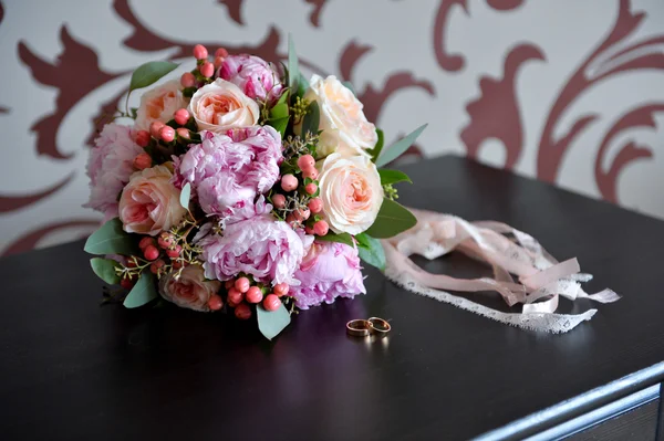 Свадебный букет на столе, рядом с кольцами — стоковое фото