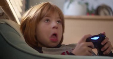 7 yaşında bir çocuk video oyunu oynarken duygusal olarak bağlanmış, elinde odaklanma ve yoğunlukla bir oyun kumandası tutuyor..