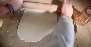 Geleneksel hamur tatlısı için ahşap mutfak masasının üstünde taze hamur topluyorum.