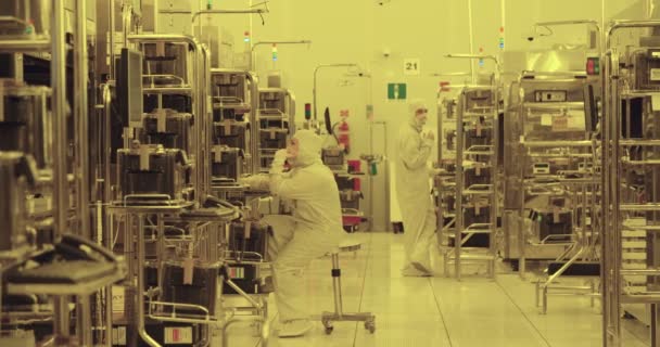 Trabalhadores com fatos limpos numa instalação de fabrico de semicondutores — Vídeo de Stock