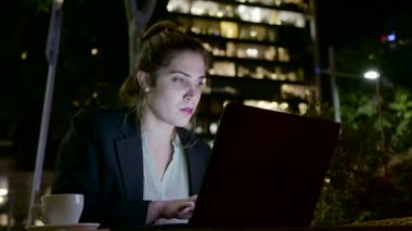 Bir dizüstü bilgisayarda çalışan ve telefon görüşmeleri yapan iş kadını
