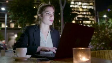 Bir dizüstü bilgisayarda çalışan ve telefon görüşmeleri yapan iş kadını