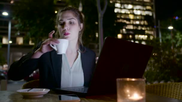 Mujer de negocios trabajando en una computadora portátil y haciendo llamadas telefónicas — Vídeo de stock