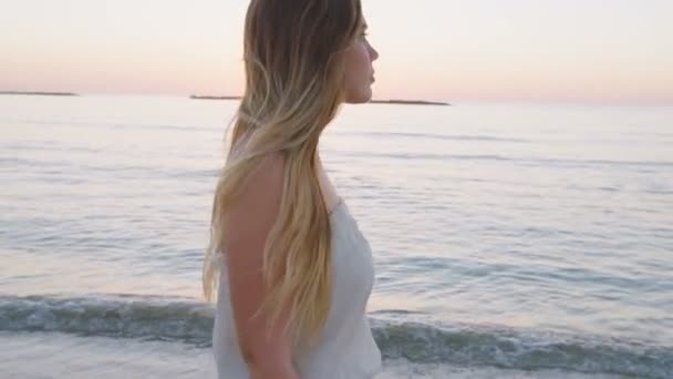 Günbatımı sırasında bir kumsalda yürüyen güzel kadın — Stok video