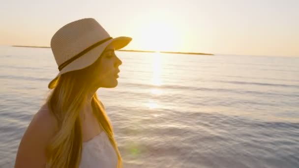 Όμορφη γυναίκα που περπατά σε μια παραλία κατά τη διάρκεια του ηλιοβασιλέματος — Αρχείο Βίντεο