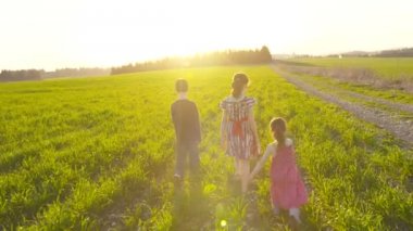 Üç çocuk günbatımı sırasında bir alanda yürüyüş
