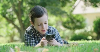 Çim döşeme bir cep telefonu ile oynayan çocuk