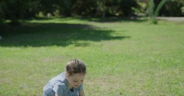 Маленькая девочка играет на улице с голубым мячом — стоковое видео