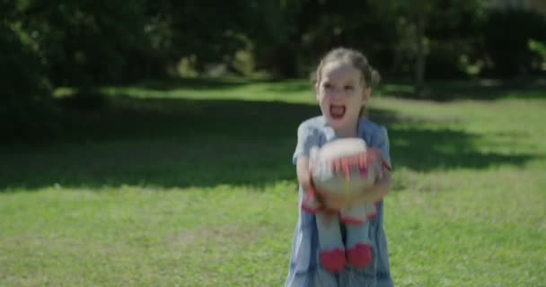Meisje met een blauwe jurk spelen met een pop — Stockvideo
