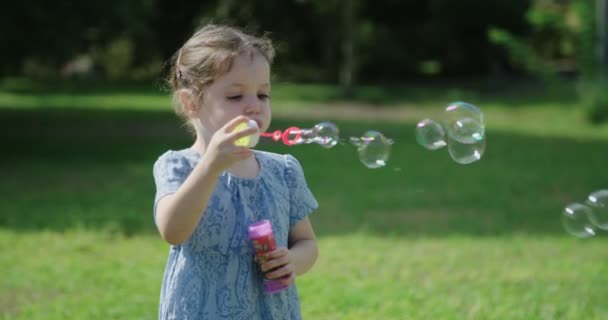 Klein meisje blazen zeepbellen — Stockvideo