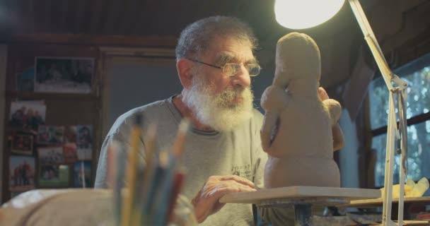 Gamla konstnären modeller en lera skulptur i en liten studio — Stockvideo