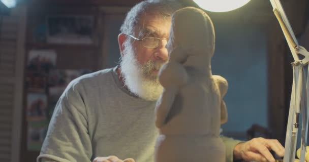 Gamla konstnären modeller en lera skulptur i en liten studio — Stockvideo