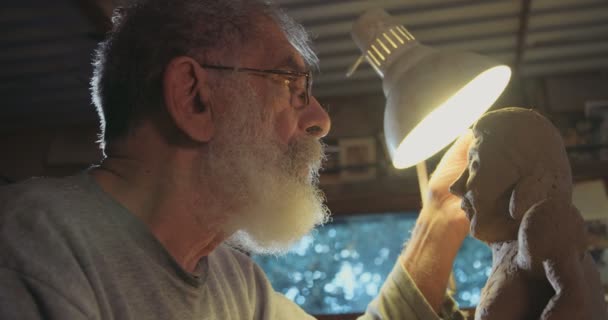 Vecchio artista modella una scultura in argilla in un piccolo studio — Video Stock