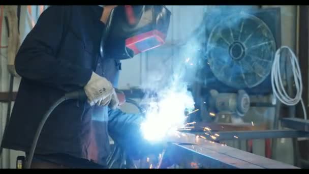 Soudeur soudant des pièces métalliques dans un atelier de soudage — Video