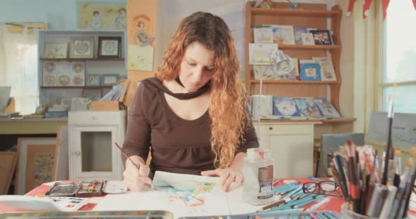Konstnär målar med vatten färger och pennor i hennes studio — Stockvideo