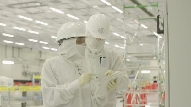 Рабочие в чистых костюмах на заводе по производству полупроводников — стоковое видео