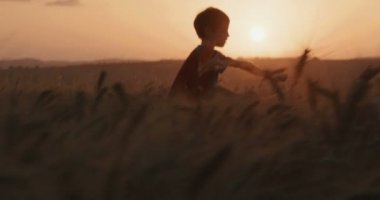 Günbatımı sırasında bir alanda çalışan Süpermen pelerini ile genç çocuk