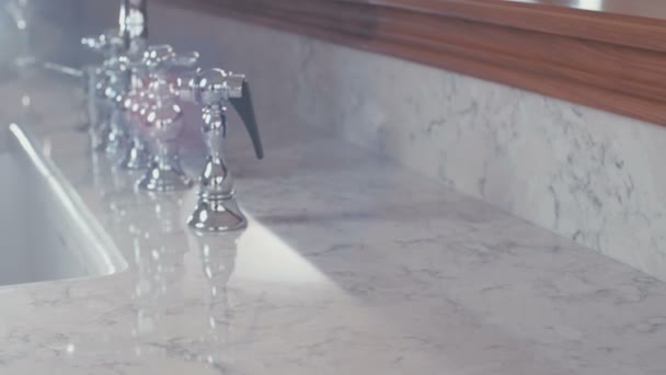 Kamerafahrt eines Luxus-Wasserhahns auf einer weißen Granitoberfläche — Stockvideo