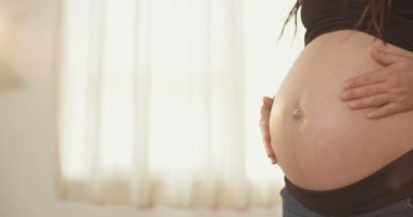 Hamile bir kadın karnını okşuyor.