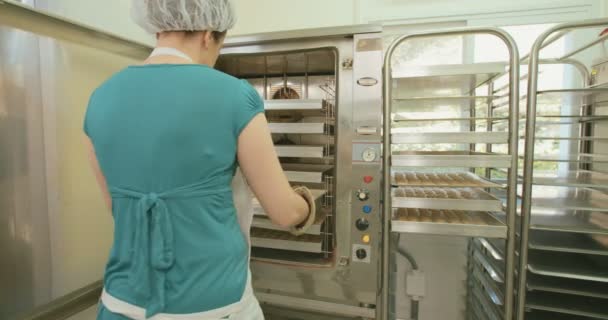 Baker taking cookies out of the oven at a bakery — Stock Video