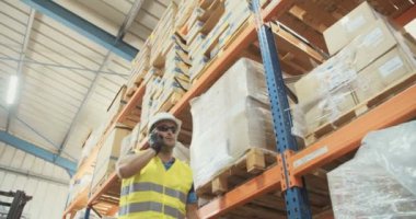 Düşük açılı izleme atış büyük bir depoda yürüyen bir lojistik işçinin