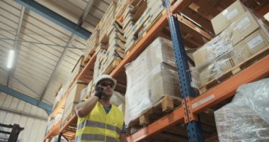 Düşük açılı izleme atış büyük bir depoda yürüyen bir lojistik işçinin